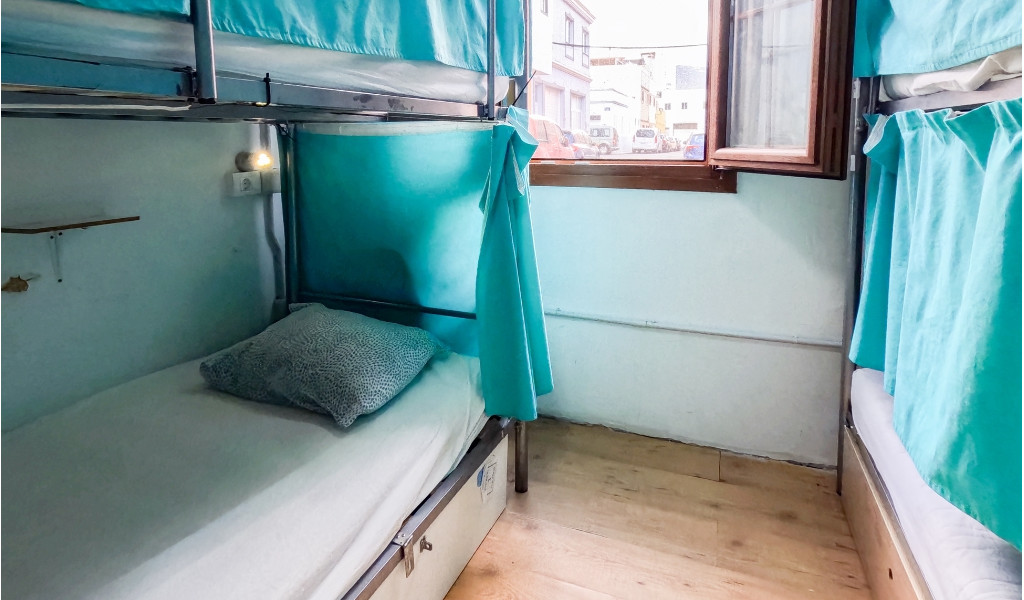 Bunk beds with teal curtains in a room with an open window in Tenerife.