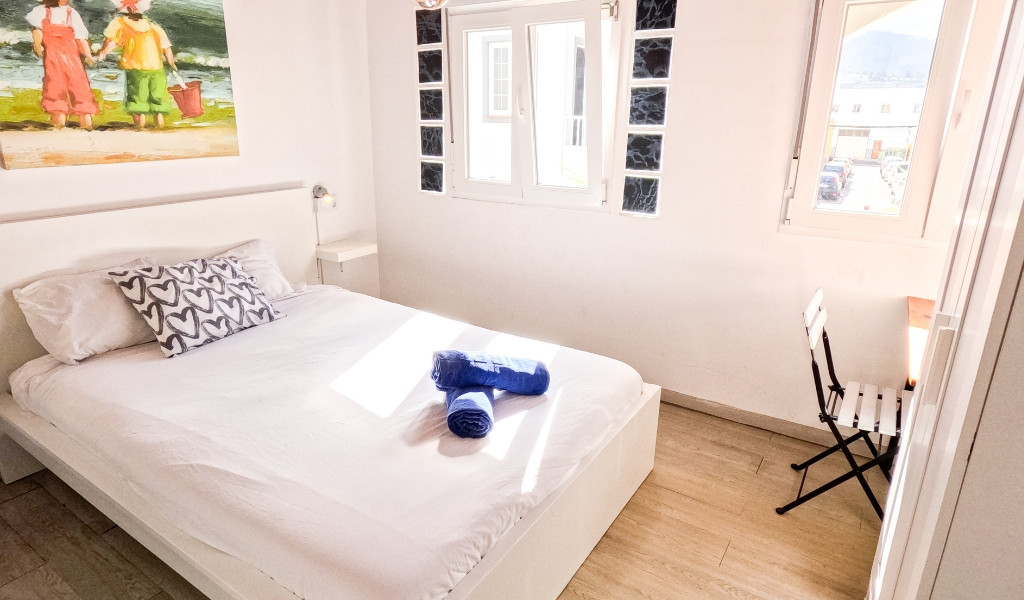 Bedroom with double bed, two blue towels, and a window view in Tenerife.