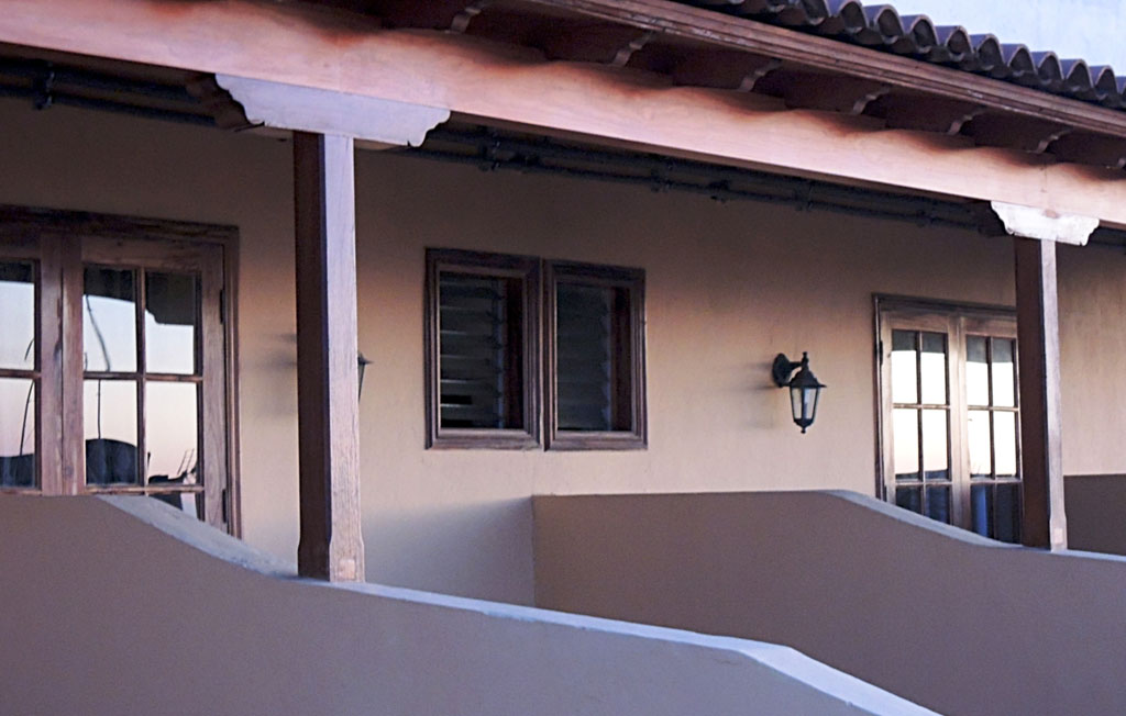 Traditional wooden balcony in Tenerife home, with wooden windows and wall lamp.