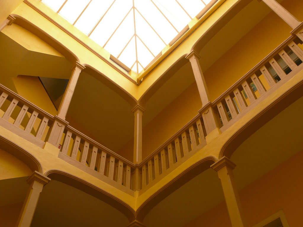 Interior de un edificio de dos pisos con pasamanos y techo de cristal en Tenerife.