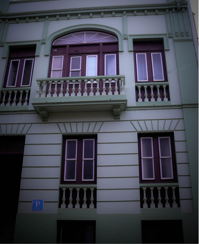 Facade of a green building with dark window frames in Santa Cruz de Tenerife.