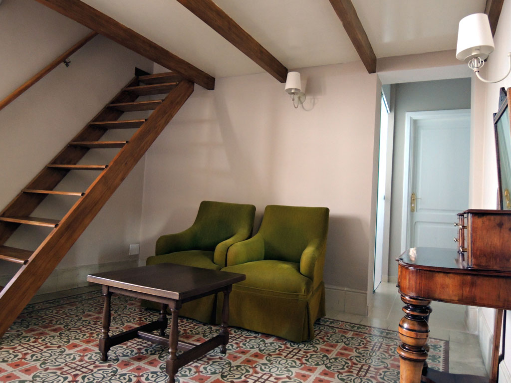Green chairs and wooden table in a cozy attic space in Tenerife house.