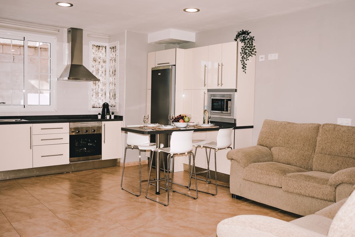 Modern kitchen and living area with dining table in Tenerife apartment.