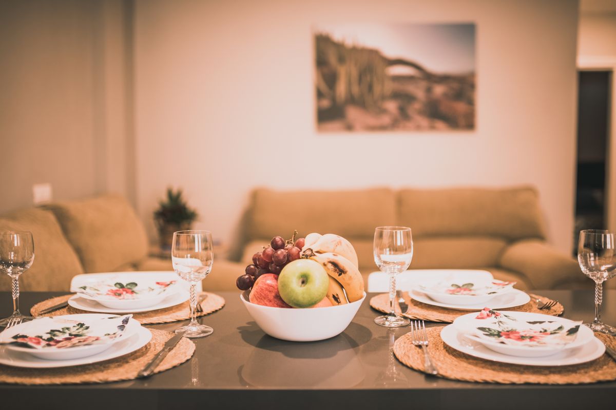 Dining table set with fruits and glassware in a Tenerife living room.
