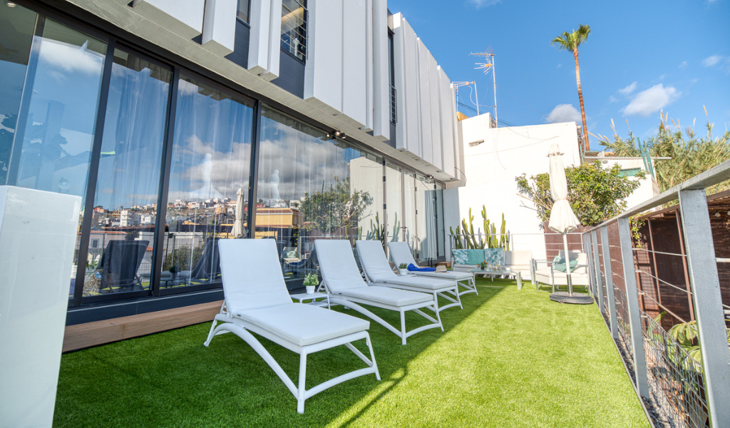 Lounge chairs on a rooftop terrace in Santa Cruz de Tenerife with city view.