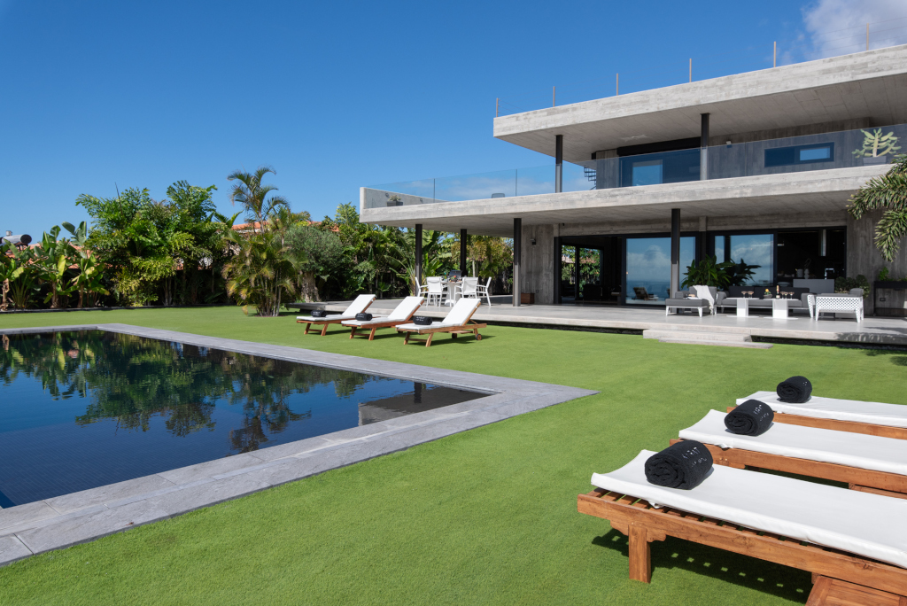 Modern villa with pool and sun loungers in Tenerife garden setting.