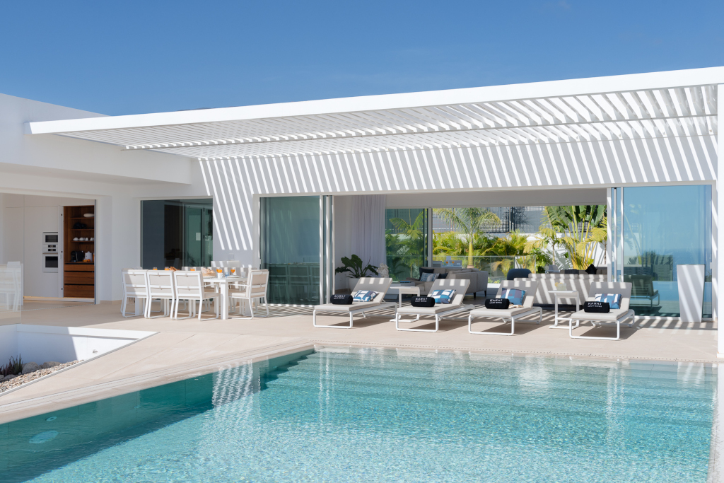 Modern villa with poolside loungers and dining area in Tenerife.