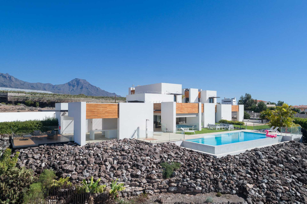 Modern villa with pool in Costa Adeje, Tenerife, with mountains in the background.