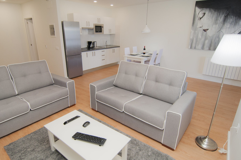 Living room with gray sofas, kitchenette, dining table in Tenerife apartment.
