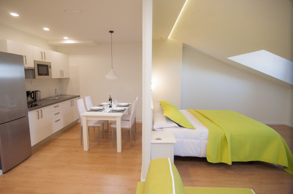 Open-plan kitchen and dining area with green-themed bedroom in Tenerife.