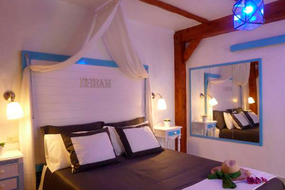 Bedroom with canopy and lamps, mirrored wall reflecting bed, text DREAM. Located in Tenerife.