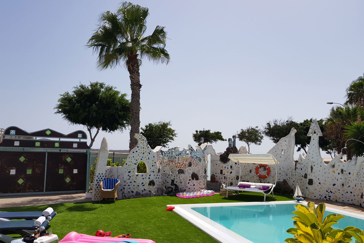 Poolside area with mosaic walls, trees, and sun loungers in Tenerife.
