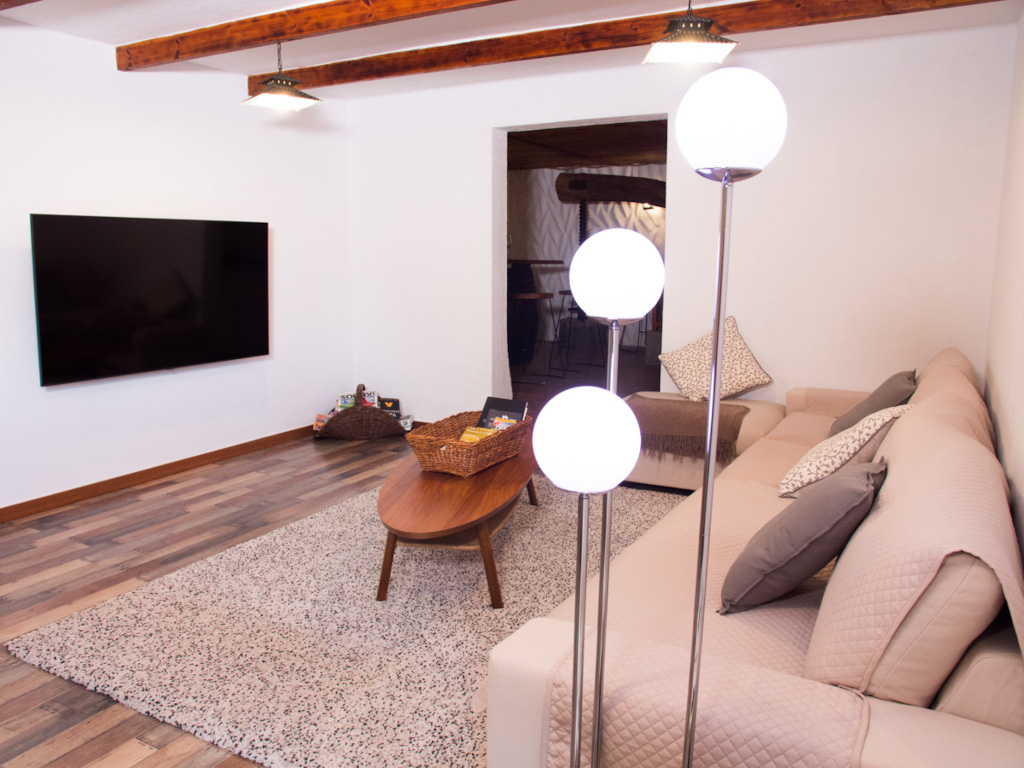 Living room in Tenerife with sofa, floor lamp, TV, and wooden coffee table.