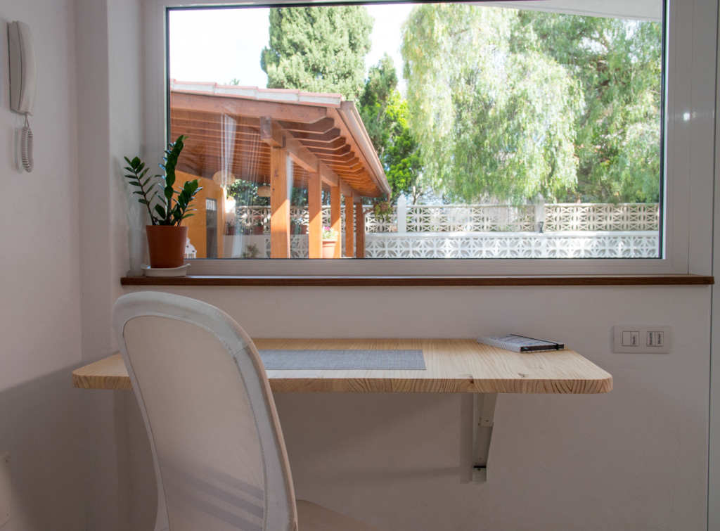 Workspace with a plant and notebook by window overlooking lush garden in Tenerife.