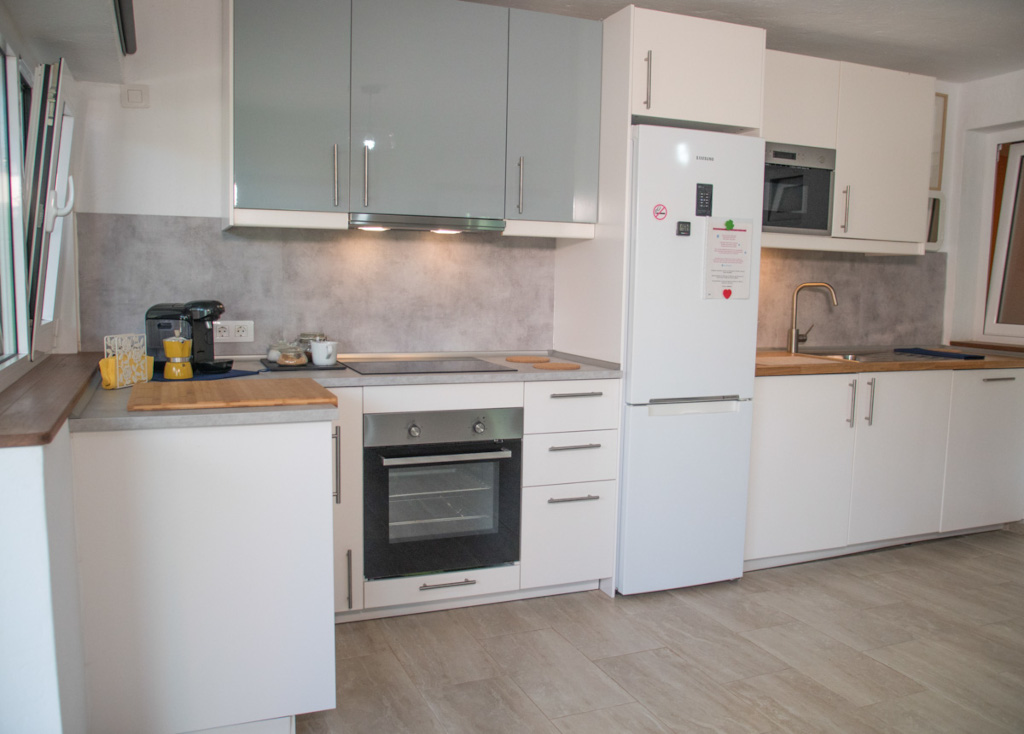 Modern kitchen in Tenerife with white cabinets, appliances, and countertop items.
