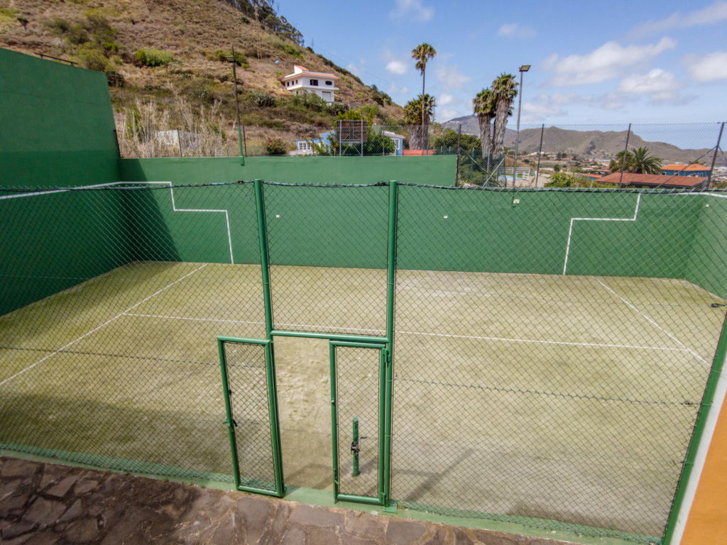 Tennis court surrounded by green walls and hills in Tenerife.