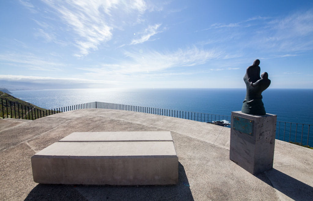 Viewpoint in Tenerife with sculpture and view of the Atlantic Ocean under clear skies.