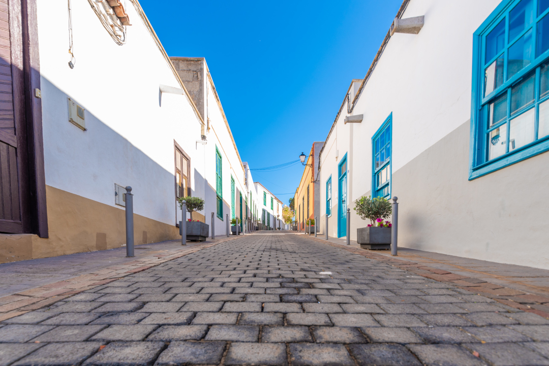 Cobbled street between white houses with blue windows in Tenerife.
