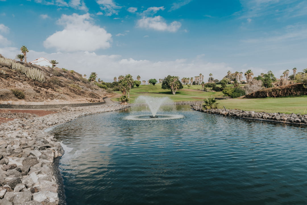 Fountain in a pond surrounded by palm trees on a golf course in Tenerife.