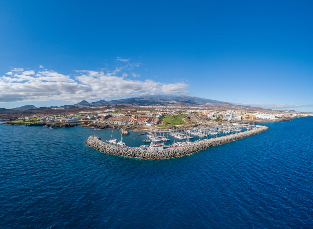 Aerial view of the marina in Tenerife with mountains in the background.