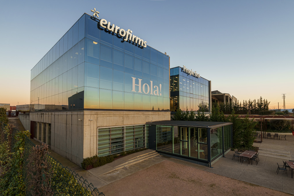 Office building with glass façade reflecting the sunset, text Hello!.