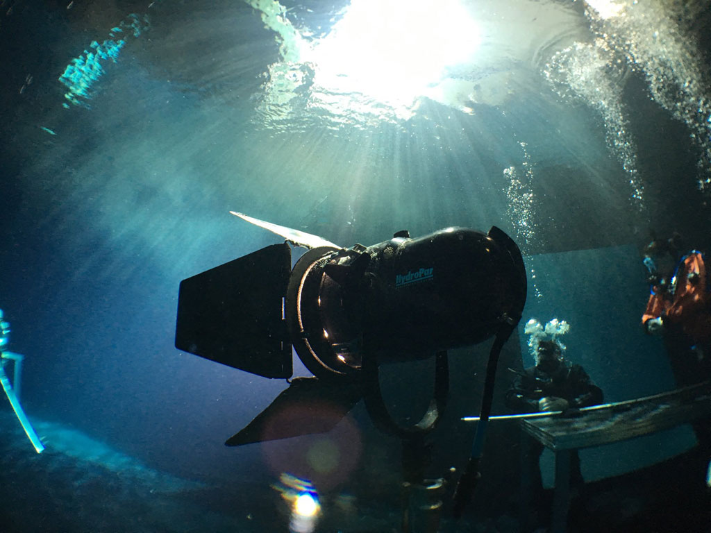 Underwater light illuminating divers in cave, Tenerife.