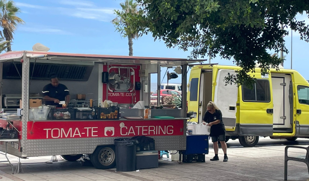 TOMA-TE Catering food truck in Tenerife with workers preparing food.