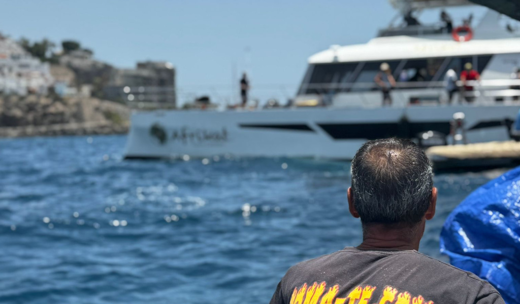 Person looking at an excursion boat at sea in Los Gigantes, Tenerife.