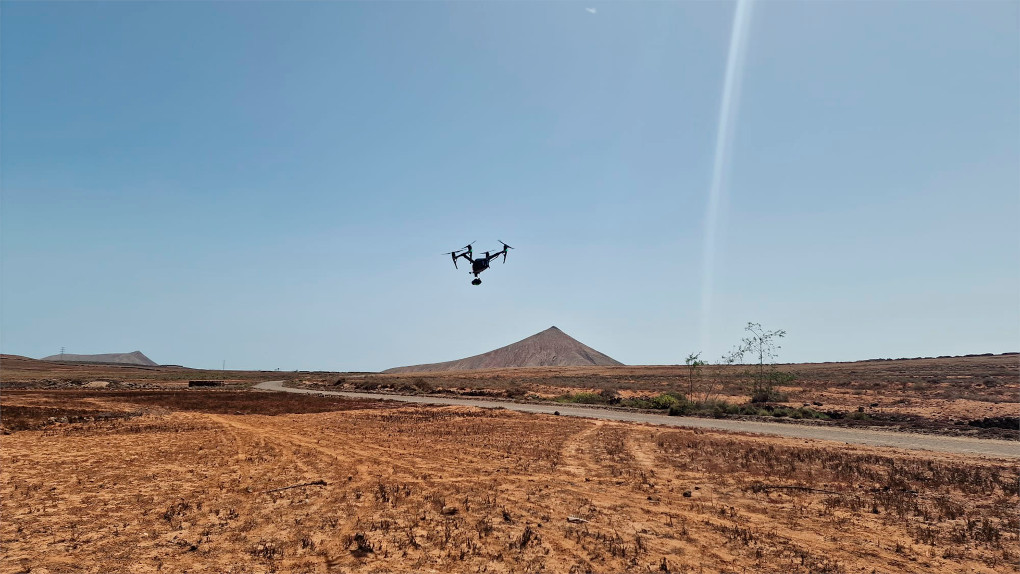 Drone flying over an arid landscape with a mountain in the background in Tenerife.