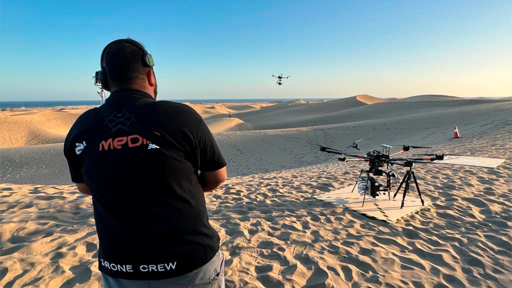 Person operating a drone in the dunes at sunset in Tenerife.