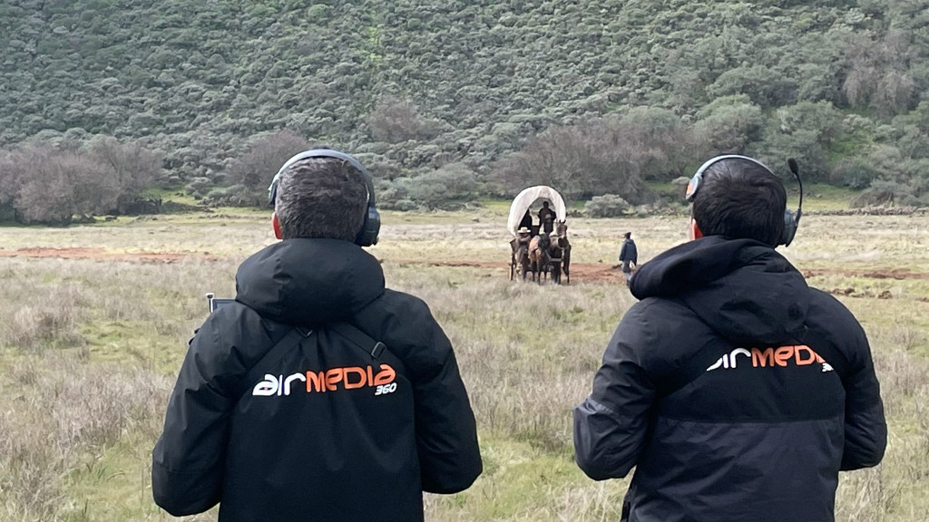 Two people observe a cart with horses in a field in Tenerife.