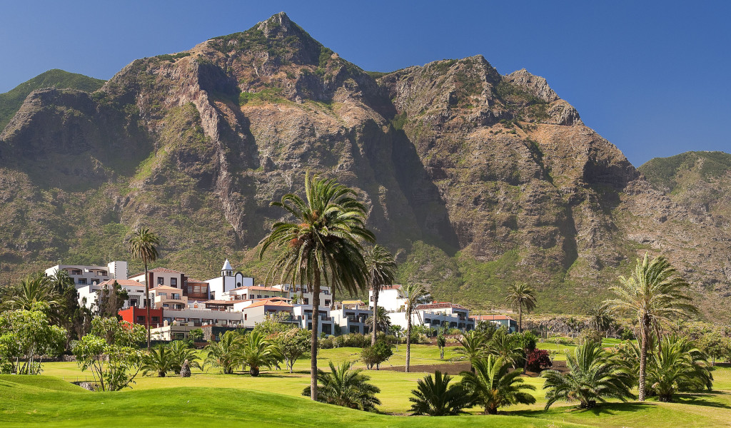 Mountainous landscape with palm trees and buildings in Buenavista del Norte, Tenerife.