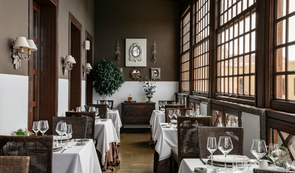 Dining room with wicker tables and chairs in front of windows in restaurant in Tenerife.