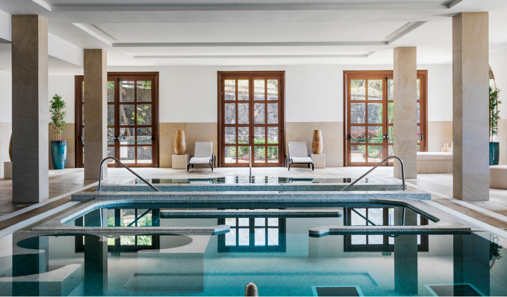 Indoor swimming pool with sun loungers and floor-to-ceiling windows in a spa in Tenerife.