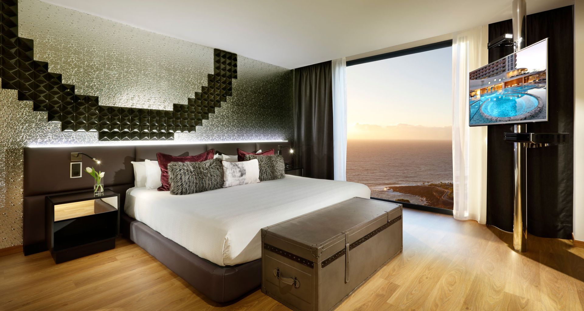 Modern room with bed, television and sea view at sunset in Tenerife.