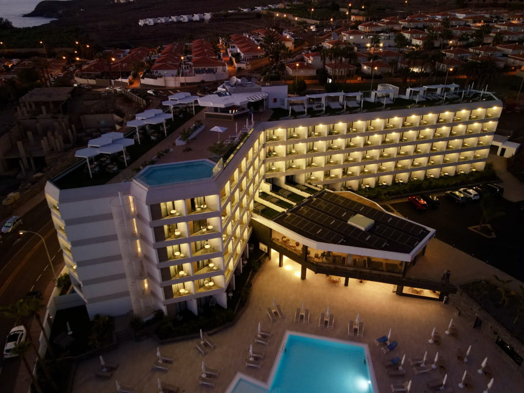 Illuminated building with rooftop pool in Tenerife at sunset.