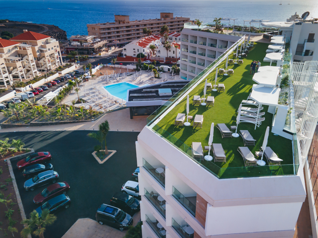 Terrace with sun loungers and parasols near the pool, Tenerife coast in the background.