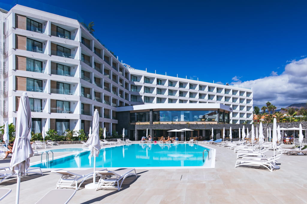 Modern hotel with pool and sun loungers in Costa Adeje, Tenerife.