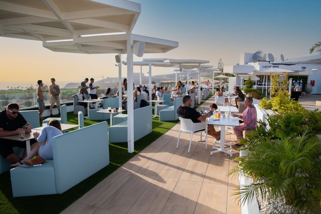 People on an outdoor terrace in La Cúspide, Tenerife, enjoying the sunset.