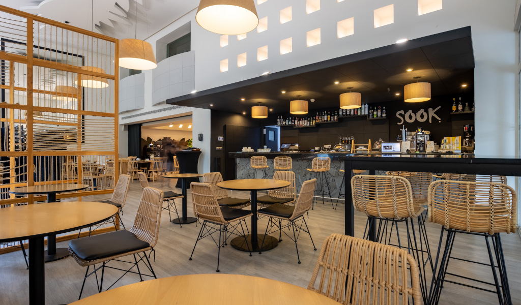 Modern and spacious bar in a restaurant in Tenerife, with wicker chairs and round tables.