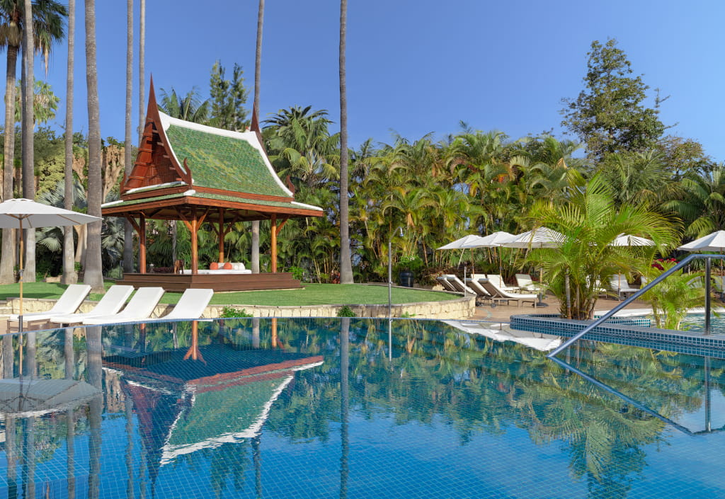 Swimming pool with sun loungers and an Asian structure surrounded by palm trees in Tenerife.