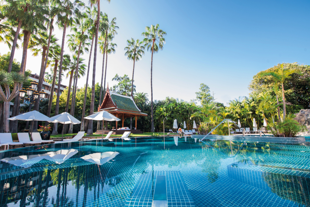 Swimming pool surrounded by palm trees and cabana in a hotel in Tenerife.