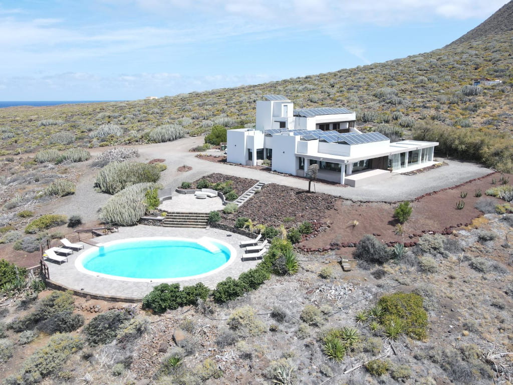 White house with swimming pool and solar panels in the arid landscape of Tenerife.