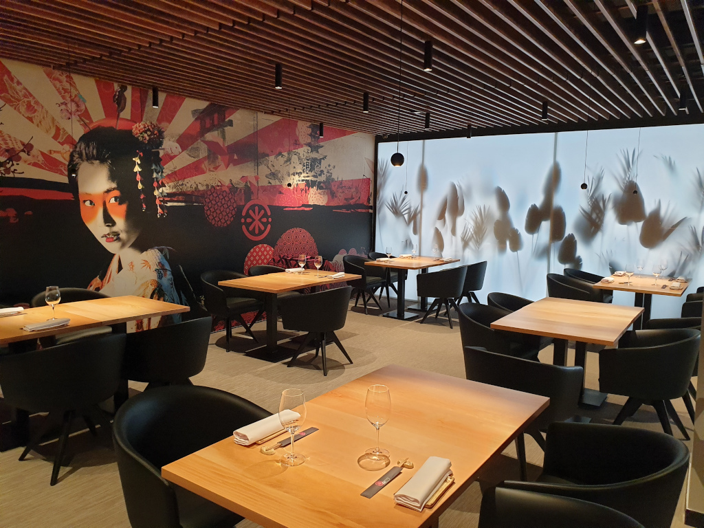 Restaurant with wooden tables and geisha mural on a wall in Tenerife.