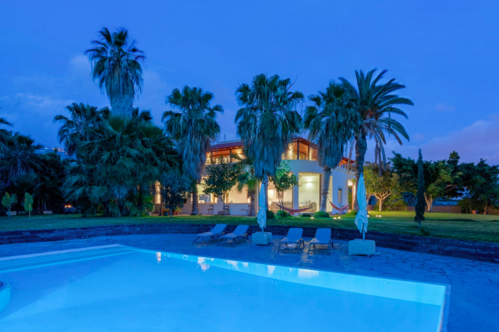 House with pool and palm trees at sunset in Tenerife.