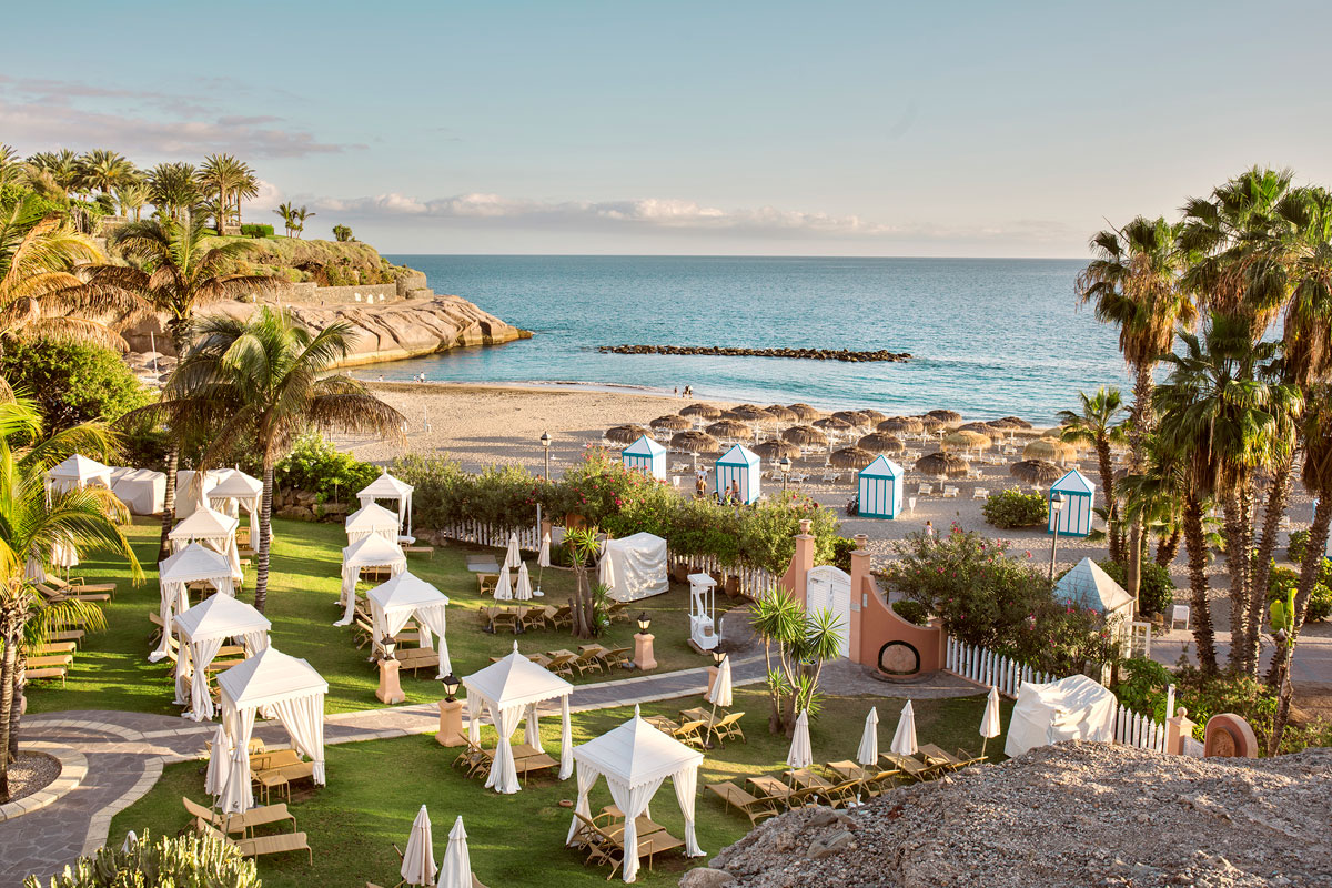 Beach with umbrellas and cabins in Costa Adeje, Tenerife, at sunset.