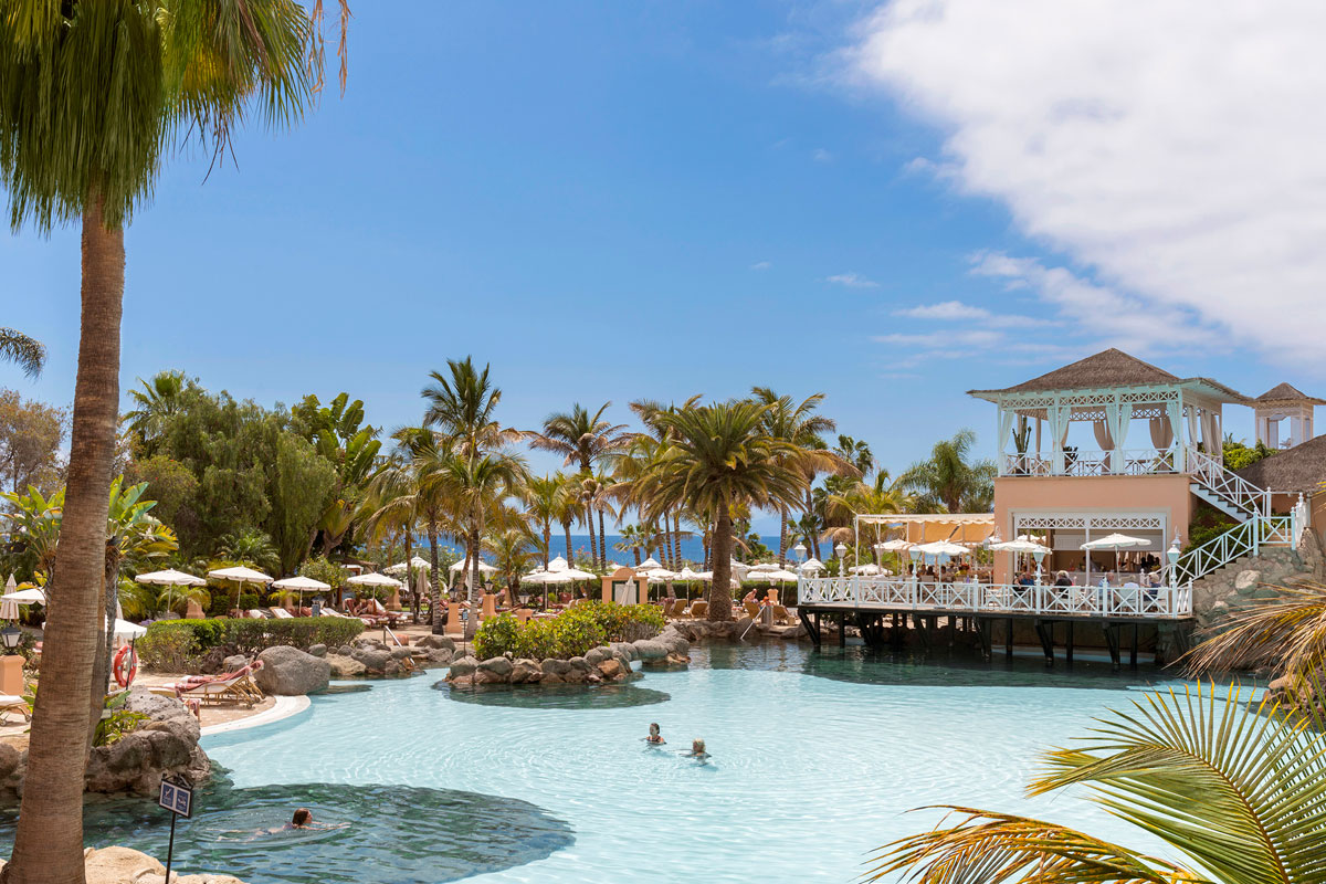 Swimming pool surrounded by palm trees and building in the Hotel in Tenerife.
