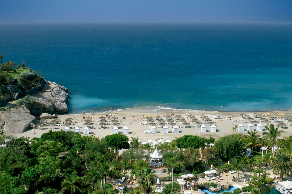 Playa del Duque in Tenerife with parasols and cabins by the sea.