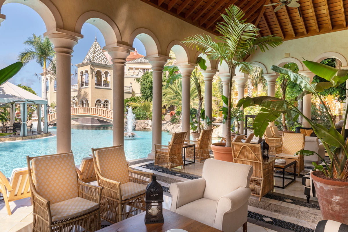 Terrace with pool and fountain in a hotel in Tenerife, surrounded by palm trees.