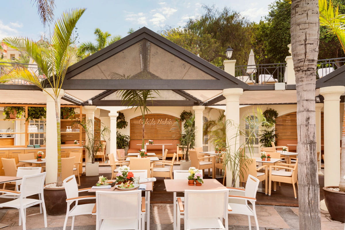 Terrace of Café La Bahía in Tenerife, with tables and greenery all around.